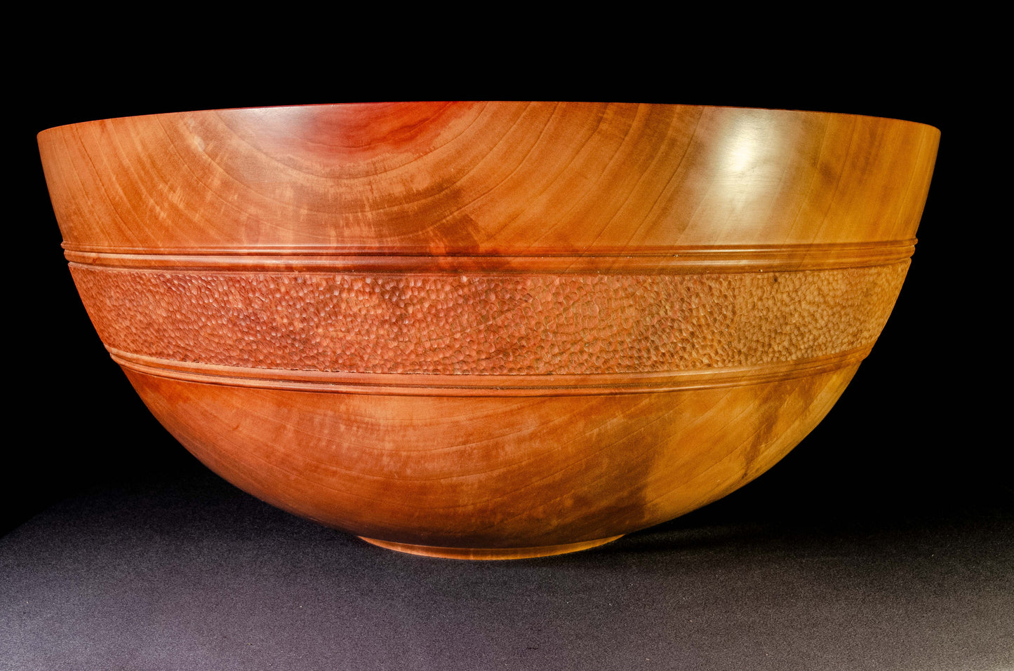 Large bowl of Pear wood with wwell-defined grain patterns. A belt of hand textured stippling encircles the bowl exterior, providing a strong visual balance and focal point. This is an heirloom bowl intended as a special gift.